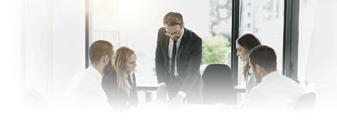 Team of business professionals in formal attire collaborating around table during office meeting with documents